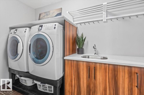 Dedicated laundry area featuring a built-in sink, durable countertop space, wood-finish cabinetry, and overhead drying racks - 219 Cranberry Bend, Fort Saskatchewan, AB - Indoor Photo Showing Laundry Room