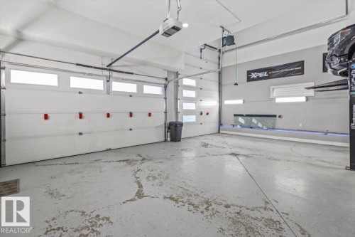 Spacious garage featuring two overhead doors with frosted window panels, high ceilings, and light gray painted walls - 219 Cranberry Bend, Fort Saskatchewan, AB - Indoor Photo Showing Garage