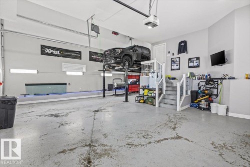 Spacious garage with light gray walls, an epoxy-coated concrete floor, and a built-in vehicle lift - 219 Cranberry Bend, Fort Saskatchewan, AB - Indoor Photo Showing Garage