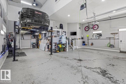 Spacious garage featuring a vehicle lift, concrete flooring, overhead lighting, and ample storage solutions - 219 Cranberry Bend, Fort Saskatchewan, AB - Indoor Photo Showing Garage