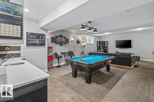Expansive recreation room featuring a built-in wet bar with a stainless steel sink, a pool table, and carpeted flooring - 219 Cranberry Bend, Fort Saskatchewan, AB - Indoor Photo Showing Other Room