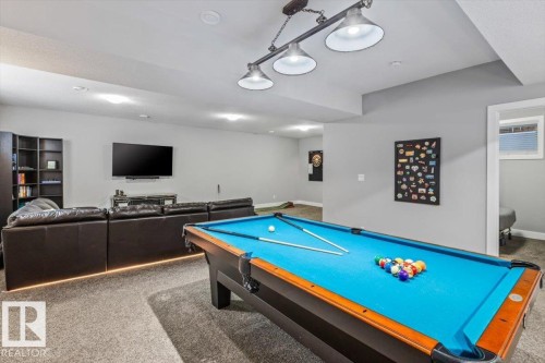 Spacious recreation room featuring a pool table with a dedicated overhead light fixture, recessed ceiling lighting, and soft carpet flooring - 219 Cranberry Bend, Fort Saskatchewan, AB - Indoor Photo Showing Other Room