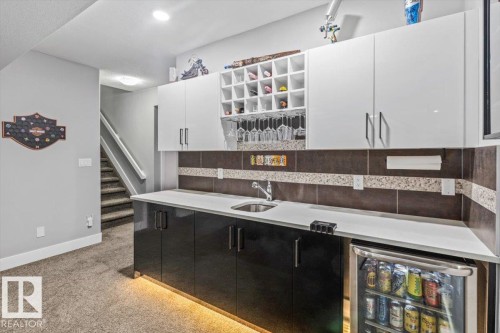 Built-in wet bar featuring a beverage refrigerator, sink, and under-cabinet lighting - 219 Cranberry Bend, Fort Saskatchewan, AB - Indoor Photo Showing Kitchen