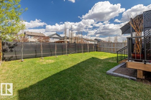 Expansive backyard featuring a manicured lawn, full fencing, and a multi-level deck with black railings - 219 Cranberry Bend, Fort Saskatchewan, AB - Outdoor