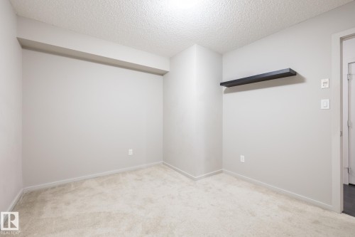 Neutral-toned room featuring light-colored carpet flooring and a textured ceiling - 131 344 Windermere Road, Edmonton, AB - Indoor Photo Showing Other Room