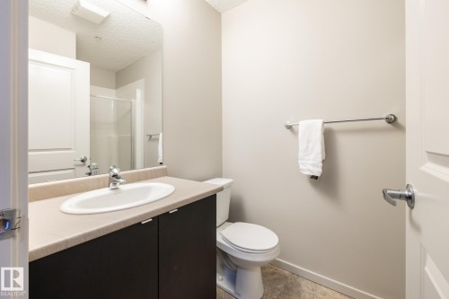 Bathroom featuring an integrated sink, dark wood-finish vanity, and a neutral countertop - 131 344 Windermere Road, Edmonton, AB - Indoor Photo Showing Bathroom