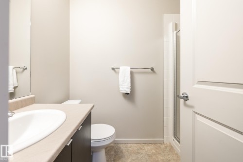 Bathroom featuring a dark wood-finish vanity with a light countertop, an undermount sink, and a glass-enclosed shower - 131 344 Windermere Road, Edmonton, AB - Indoor Photo Showing Bathroom