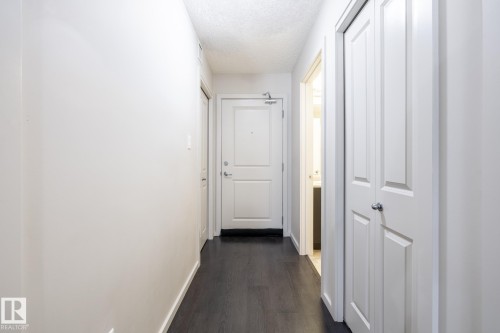Entryway featuring dark wood-finish flooring, white walls, and a paneled front door - 131 344 Windermere Road, Edmonton, AB - Indoor Photo Showing Other Room