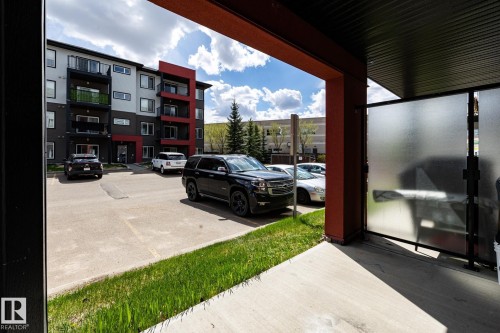 Multi-story residential building with modern exterior finishes, private balconies, and an adjacent parking area - 131 344 Windermere Road, Edmonton, AB - Outdoor