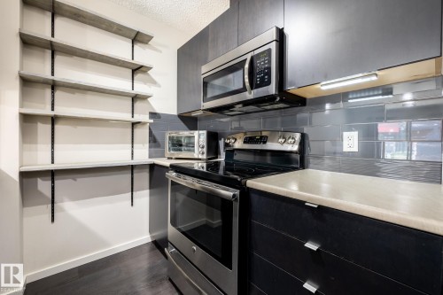 Modern kitchen featuring dark wood-finish cabinetry and light-colored countertops - 131 344 Windermere Road, Edmonton, AB - Indoor Photo Showing Kitchen