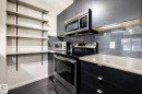 Modern kitchen featuring dark wood-finish cabinetry and light-colored countertops - 131 344 Windermere Road, Edmonton, AB  - Indoor Photo Showing Kitchen 