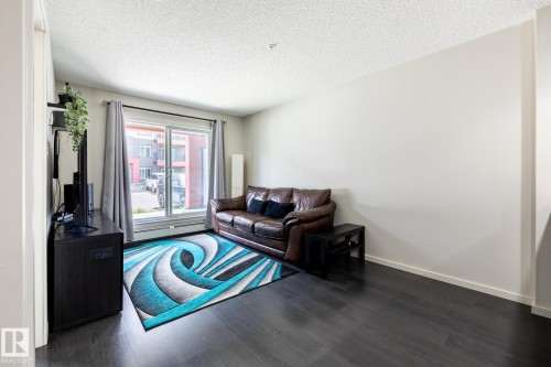 Spacious living area featuring dark wood-finish flooring and light-toned walls - 131 344 Windermere Road, Edmonton, AB - Indoor Photo Showing Living Room