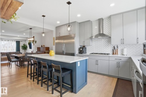 Modern kitchen featuring light gray cabinetry, stainless steel appliances, a white herringbone tile backsplash, and a blue island with a white countertop - 2116 159 Street, Edmonton, AB - Indoor Photo Showing Kitchen With Upgraded Kitchen