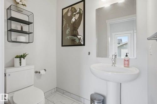 Pedestal sink with chrome faucet, complemented by a rectangular frameless mirror and an overhead light fixture - 2116 159 Street, Edmonton, AB - Indoor Photo Showing Bathroom