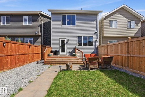 Backyard featuring a wooden deck with railing, a stone patio area, and a grassy expanse - 2116 159 Street, Edmonton, AB - Outdoor With Exterior