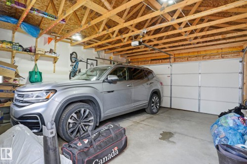 Attached garage with an overhead door, exposed wood ceiling joists, and a concrete floor - 2116 159 Street, Edmonton, AB - Indoor Photo Showing Garage