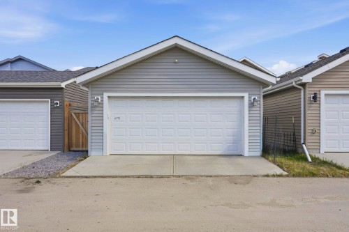 Detached garage featuring panel garage door, light grey siding, and concrete driveway - 2116 159 Street, Edmonton, AB - Outdoor