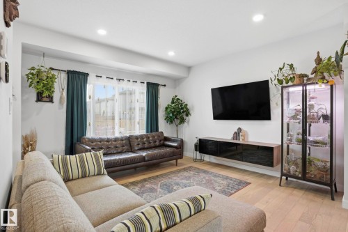 Bright living area featuring light wood-finish flooring, recessed lighting, and a large window with sheer and blackout curtains - 2116 159 Street, Edmonton, AB - Indoor Photo Showing Living Room