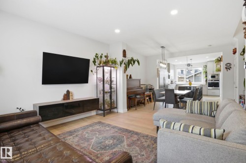 Open-concept living area with light wood-finish flooring, recessed lighting, and a modern floating media console - 2116 159 Street, Edmonton, AB - Indoor Photo Showing Living Room