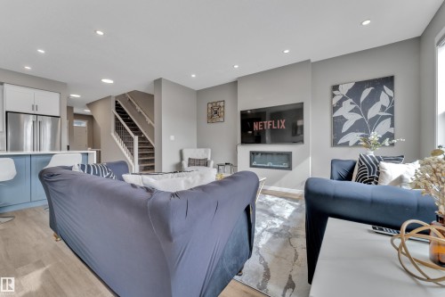 Living area featuring recessed lighting, light-toned flooring, and a modern fireplace - 21853 98A Avenue, Edmonton, AB - Indoor Photo Showing Living Room With Fireplace