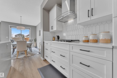 The kitchen features white cabinetry with dark hardware, a white subway tile backsplash, and a stainless steel range hood - 21853 98A Avenue, Edmonton, AB - Indoor Photo Showing Kitchen With Upgraded Kitchen