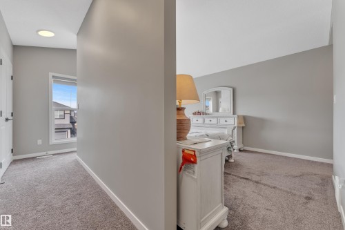 This interior features neutral gray walls and carpeting, a white interior door with black hardware, and a window providing natural light - 21853 98A Avenue, Edmonton, AB - Indoor
