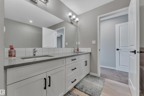 Well-appointed bathroom featuring a double vanity with white cabinetry, a light gray countertop, and a large mirror - 21853 98A Avenue, Edmonton, AB - Indoor Photo Showing Bathroom