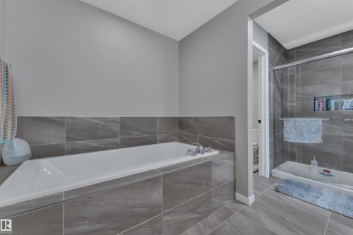 Bathroom featuring a built-in bathtub with chrome fixtures, and a shower with a glass enclosure and built-in shelving - 21853 98A Avenue, Edmonton, AB - Indoor Photo Showing Bathroom