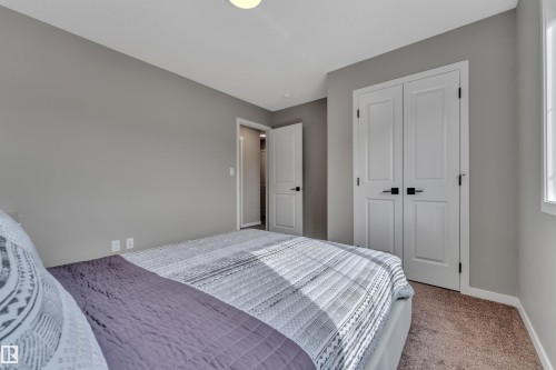 This room features a neutral color palette, wall-to-wall carpeting, and white doors with dark hardware - 21853 98A Avenue, Edmonton, AB - Indoor Photo Showing Bedroom