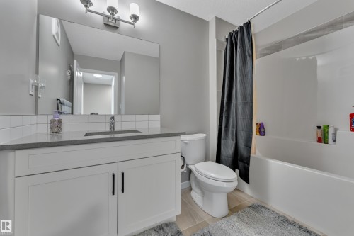 The bathroom features a modern vanity with white cabinetry, a large mirror, and a full-size bathtub with a shower - 21853 98A Avenue, Edmonton, AB - Indoor Photo Showing Bathroom