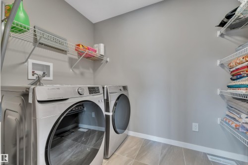 This laundry room features light gray walls, light-colored tile flooring, and white wire shelving - 21853 98A Avenue, Edmonton, AB - Indoor Photo Showing Laundry Room