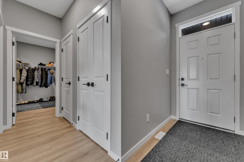 The entryway features light wood flooring, a white paneled door with a transom window, and two white doors with dark hardware - 21853 98A Avenue, Edmonton, AB - Indoor Photo Showing Other Room