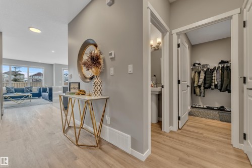 This entrance features light-toned flooring, a decorative console table with a mirror, and a convenient coat closet with shelving - 21853 98A Avenue, Edmonton, AB - Indoor Photo Showing Other Room