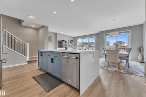 The kitchen features a large island with blue cabinetry, a white countertop, and a stainless steel dishwasher - 21853 98A Avenue, Edmonton, AB - Indoor