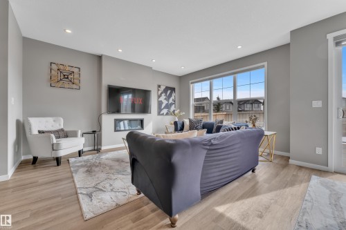 This inviting living area features light-toned flooring, recessed lighting, and a modern fireplace integrated into the wall - 21853 98A Avenue, Edmonton, AB - Indoor Photo Showing Living Room