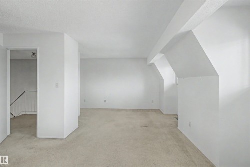 Spacious room featuring neutral carpeting, white painted walls, and textured ceilings - 5953 40 Avenue, Edmonton, AB - Indoor Photo Showing Other Room