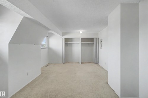 Carpeted room featuring white walls, a single window, and two integrated closet spaces with bi-fold doors - 5953 40 Avenue, Edmonton, AB - Indoor Photo Showing Other Room