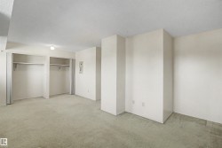 Spacious room featuring light-colored carpeting, white walls, and a ceiling-mounted light fixture - 