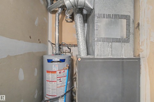 Utility area featuring a water heater, furnace, and exposed ductwork - 5953 40 Avenue, Edmonton, AB - Indoor Photo Showing Basement