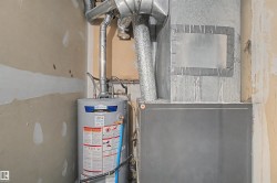 Utility area featuring a water heater, furnace, and exposed ductwork - 