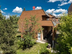 Multi-level exterior featuring a wood-shingle roof, wood-plank siding, and mature greenery - 