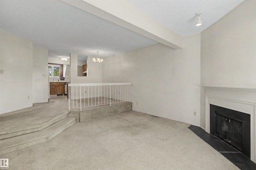 Living area featuring a fireplace with a white mantel and dark hearth, track lighting, and carpeted flooring - 5953 40 Avenue, Edmonton, AB - Indoor With Fireplace
