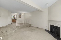 Living area featuring a fireplace with a white mantel and dark hearth, track lighting, and carpeted flooring - 