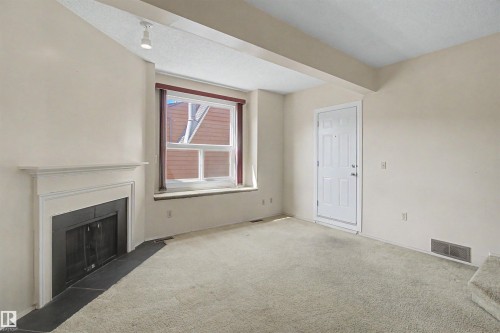 Living area featuring a fireplace with a white mantel and black hearth - 5953 40 Avenue, Edmonton, AB - Indoor With Fireplace