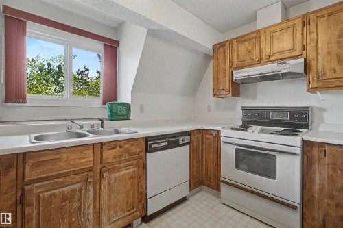 Kitchen featuring wood-finish cabinetry, white countertops, and a double basin stainless steel sink - 5953 40 Avenue, Edmonton, AB - Indoor Photo Showing Kitchen With Double Sink