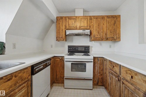 U-shaped kitchen layout featuring wood cabinetry, white countertops, and a built-in dishwasher - 5953 40 Avenue, Edmonton, AB - Indoor Photo Showing Kitchen