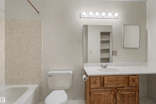Full bathroom featuring a single vanity with wood-finish cabinetry, a large mirror, and a built-in medicine cabinet - 5953 40 Avenue, Edmonton, AB - Indoor Photo Showing Bathroom