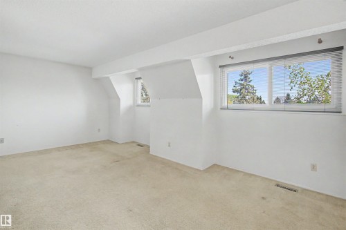 Spacious room featuring neutral carpeting, white walls, and two windows with horizontal blinds - 5953 40 Avenue, Edmonton, AB - Indoor Photo Showing Other Room