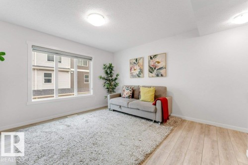 Bright room featuring a large multi-pane window, flush-mount ceiling lighting, light wood-finish flooring, and white baseboards - 53 1110 Daniels Link Link, Edmonton, AB - Indoor Photo Showing Living Room