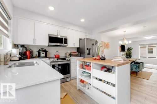 Bright kitchen featuring white cabinetry, stainless steel appliances, light-toned countertops, wood-finish flooring, and recessed lighting - 53 1110 Daniels Link Link, Edmonton, AB - Indoor Photo Showing Kitchen With Stainless Steel Kitchen With Double Sink With Upgraded Kitchen